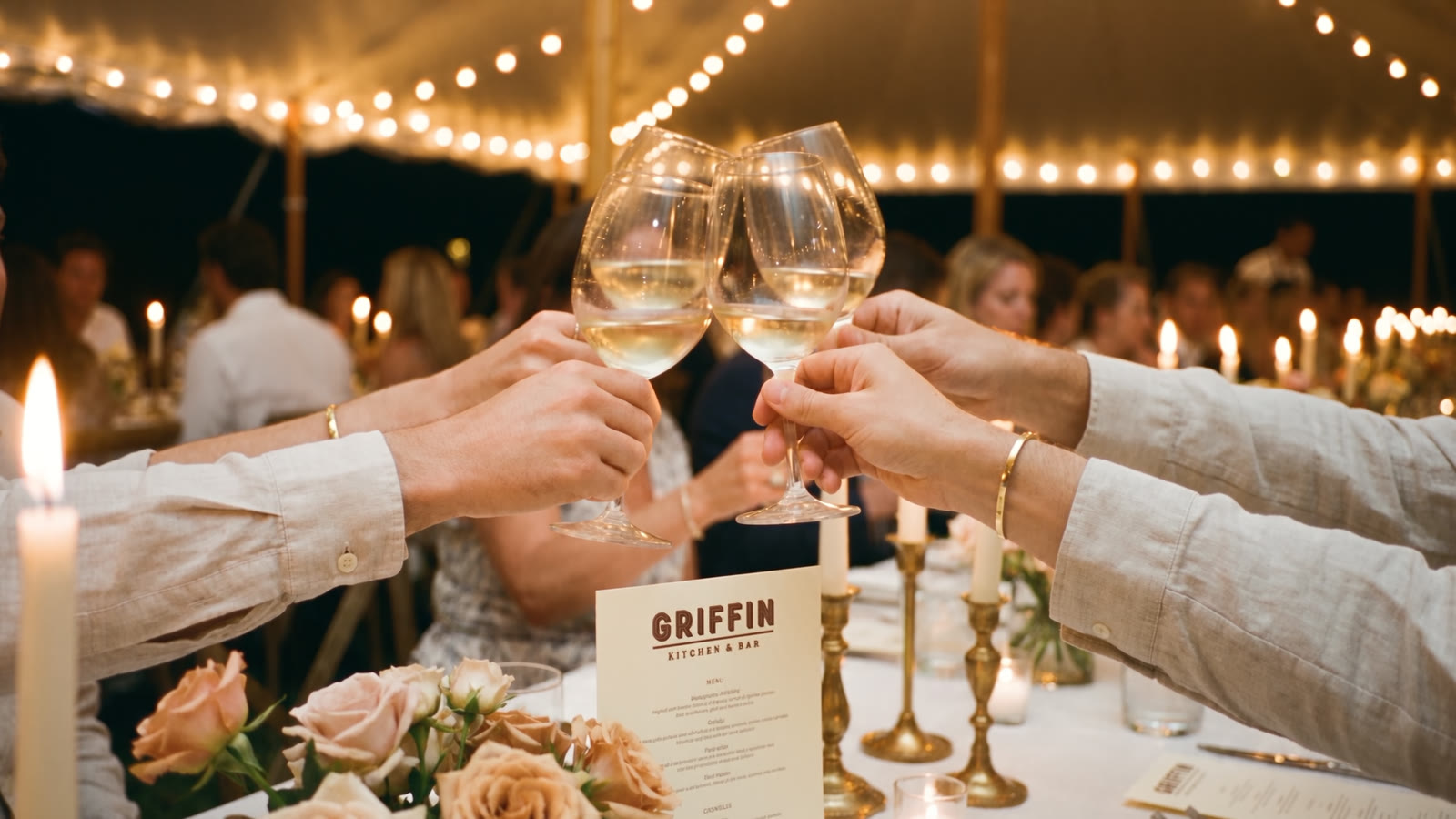 Guests raising a toast at a candlelit tented dinner